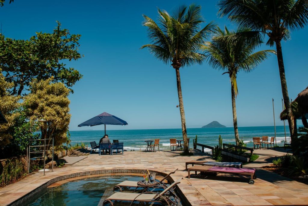 Área de praia da Pousada Chez Louise et Louis com palmeiras e vista para o mar